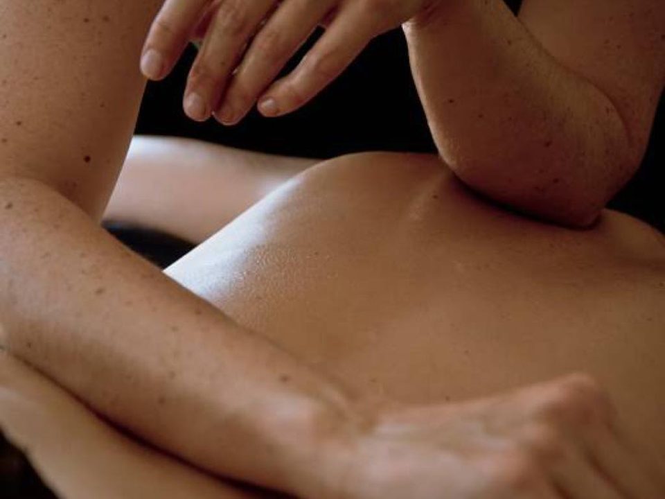 Ein Unterarm gleitet über den Rücken einer liegenden Person, bei einer Lomi-Lomi-Massage